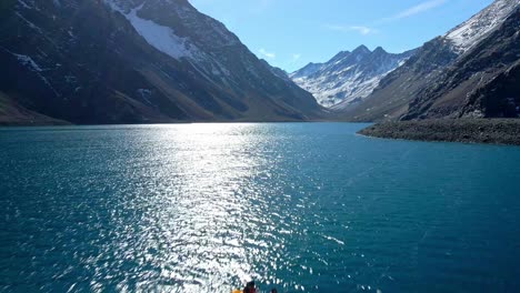Aerial-dolly-in-view-of-a-couple-in-a-kayak-on-the-Laguna-del-Inca,-in-the-Chilean-Andes,-near-the-Chile-Argentina-border