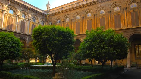 Pan-shot-of-an-empty-courtyard-of-Doria-Pamphilj-gallery-in-Rome,-Italy-with-garden-trees-in-the-centre-of-the-courtyard-at-daytime