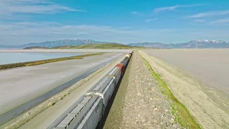 AERIAL---Train-on-railway,-Great-Salt-Lake,-Utah,-forward-tracking-shot