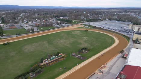 Aerial-view-of-Horses-competing-at-a-race-track-in-Charles-town,-USA---tilt,-drone-shot