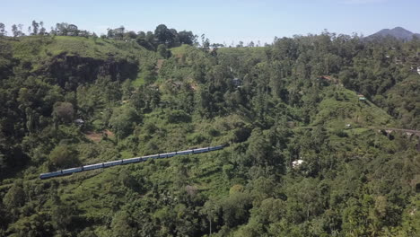 Aerial:-Passenger-train-approaches-famous-Nine-Arch-Bridge,-Sri-Lanka