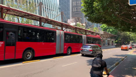 Largo-Rojo-Articulado-Rojo-Metrobús-De-La-Ciudad-De-México-Pasando-Por-Un-Carril-Exclusivo-Para-Autobuses-En-La-Ciudad-De-México