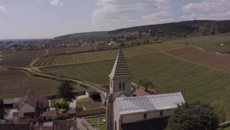 Drone-flyover-historic-Fixin-church,-reveal-scenery-of-famous-vineyards,-Burgundy