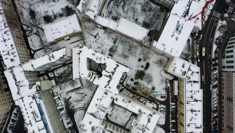 Aerial-view-above-snow-covered-roofs-in-Warsaw,-winter-in-Poland---birds-eye,-drone-shot