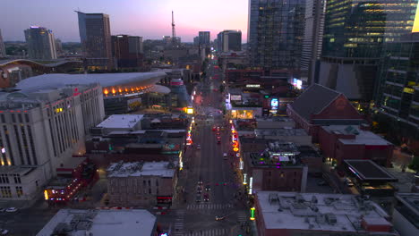 Aerial-view-of-the-Broadway-street-and-downtown-Nashville,-USA,-during-dusk---reverse,-tilt,-drone-shot
