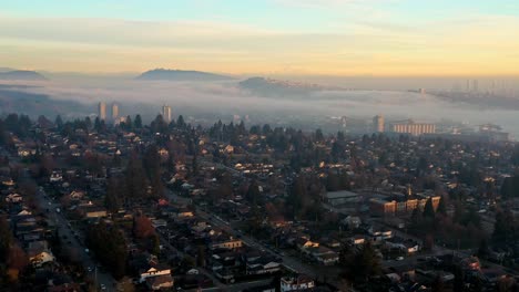 Stunning-Sunset-Fog-over-North-Vancouver-Neighborhood-Homes-and-Rental-Apartments-in-Canada---Drone-Aerial-Forward-Flying-in-the-Sky,-Wispy-Clouds-and-Orange-Teal-Colors,-SFU-and-Mount-Baker,-in-UHD