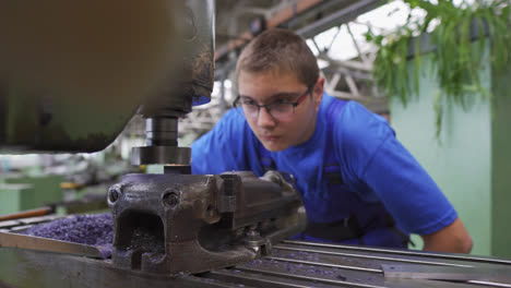 Young-male-student-working-closely-with-a-metal-lathe-on-a-project-in-a-high-school-workshop