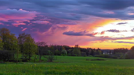 Wolken-Ziehen-Im-Zeitraffer-Am-Sonnenuntergangshimmel-über-Einer-Wunderschönen-Ländlichen-Grünen-Feldlandschaft-Mit-Gelben-Blumen-Vorbei