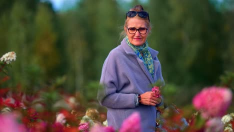 Senior-Woman-Holding-A-Flower-While-Walking-In-Flower-Fields-Park