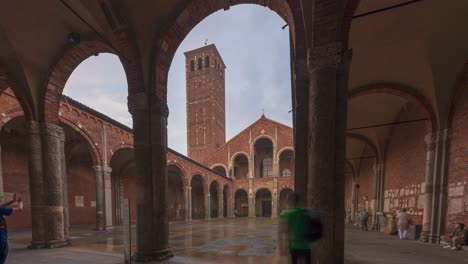 Time-lapse-of-Saint-Ambrogio-church-brick-building-with-bell-towers,-courtyard,-arches-at-rainy-day,-Milan,-Lombardy,-Italy