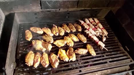 Chicken-wings-and-skewers-on-charcoal-grill-roasting-on-hot-mesh-and-smoke-coming-out