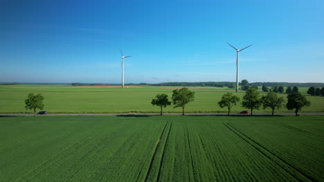 Landstraße-In-Immergrünen-Feldern-Mit-Hoch-Aufragenden-Windkraftanlagen-Im-Hintergrund