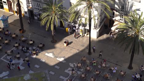 Looking-down-at-typical-Mediterranean-square-with-café-tables-and-palm-trees