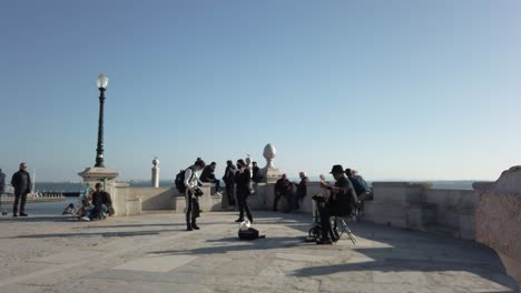 Musician-Performing-On-Cais-das-Colunas-With-Tourists-Looking-On