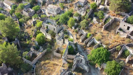 aerial-top-down-view-of-the-abandoned-ghost-village-of-Kayakoy-in-Fethiye-Turkey-on-a-sunny-day-with-only-ruins-left-surrounded-by-overgrown-trees