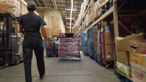 Following-View-of-Young-Man-Walking-Through-Working-Industrial-Warehouse
