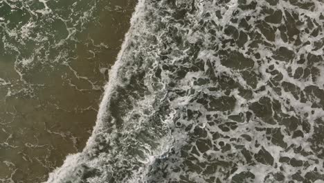 Waves-breaking-along-shoreline-of-beach-Top-down-aerial