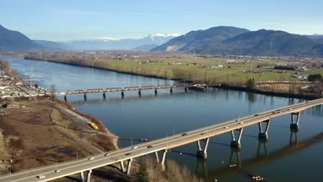 Aerial-View-Of-Mission-Bridge-And-Railway-Bridge-Over-The-Fraser-River-In-Mission,-BC,-Canada---drone-shot