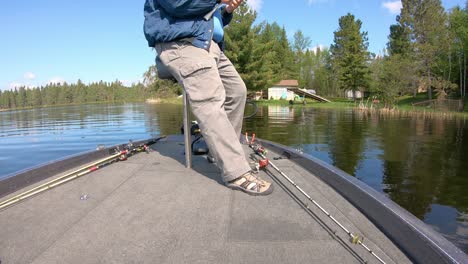 Man-fishing-with-an-open-face-reel-and-artificial-lure-while-leaning-on-a-butt-seat-in-the-front-of-a-bass-boat