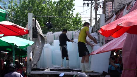 Man-unloading-huge-blocks-of-ice-from-a-truck-to-be-used-at-the-Khlong-Toei-Market-in-Bangkok