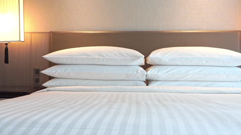 Hotel-room-bedding---bed-with-6-pillows-and-turned-on-night-lights---pan-right