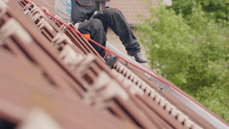 Blick-Auf-Kniehöhe-Eines-Arbeiters,-Der-Am-Tag-Ein-Solarpanel-Auf-Dem-Dach-Installiert