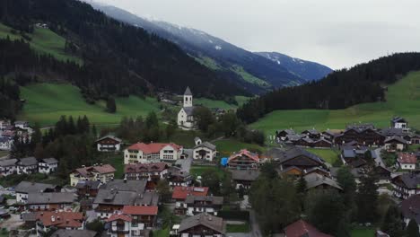Aereai-video-taken-with-DJI-Mavic-2-Pro-of-a-small-town-in-Trentino-Alto-Adige-with-a-church-in-the-middle,-the-video-shows-the-small-town-and-the-mountains-in-the-background
