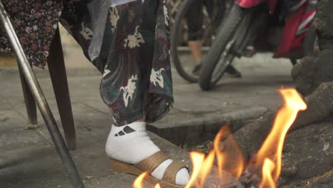 Old-Lady-burning-money-on-a-fire-on-the-street,-Hanoi-Vietnam