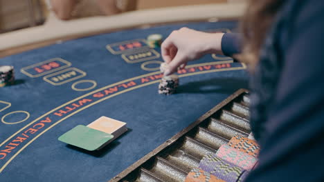 Slow-motion-shot-of-a-casino-dealer-dressed-in-blue-placing-bets-at-the-blackjack-table