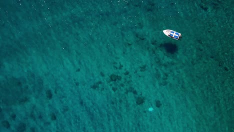 Drohnenaufnahmen-Der-Anthony-Quinn-Bucht-Auf-Der-Insel-Rhodos,-Wo-Ein-Boot-Ruhig-Auf-Dem-Azurblauen-Wasser-Des-Mittelmeers-Schwimmt
