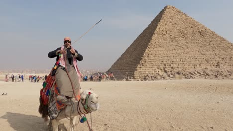 Man-on-a-camel-near-Pyramid-at-Giza-complex,-Cairo-Egypt