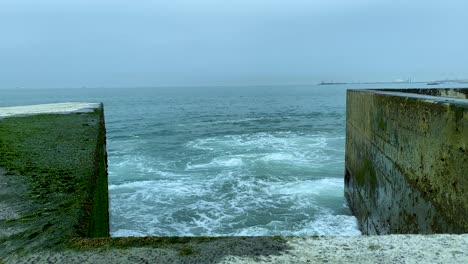 A-stormy-ocean-slams-against-a-concrete-breakwater---Pontão-da-Barra-do-Douro---Molhe-Norte,-Porto,-Portugal