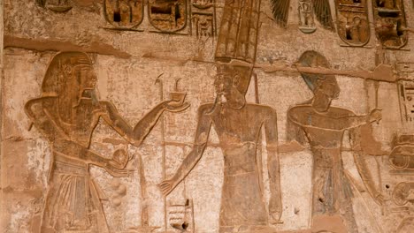 Detail-of-ancient-Egyptian-hieroglyphs-of-people-and-god-on-a-wall,-Habu-Temple,-Luxor,-Egypt