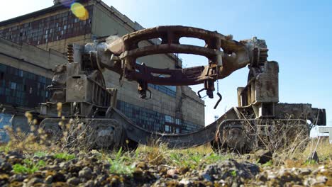 Exterior-view-of-abandoned-Soviet-heavy-metallurgy-melting-factory-Liepajas-Metalurgs-territory,-rust-covered-railway-transport-vehicle,-sunny-day,-wide-low-angle-shot