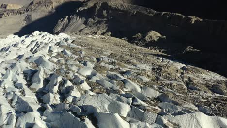 Luftdrohne-Fliegt-über-Die-Gletscherspalten-Des-Passu-Gletschers-In-Hunza,-Pakistan,-Zusammen-Mit-Schmutz-Und-Felsen,-Gemischt-Mit-Dem-Weißen-Schnee-Zwischen-Den-Passu-Kegelbergen,-Während-Des-Sonnenuntergangs-Im-Sommer