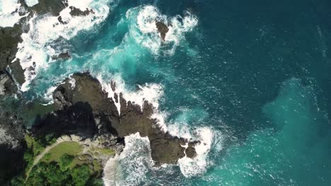 Luftaufnahme-Von-Wellen-Des-Indischen-Ozeans,-Die-Bei-Sonnigem-Wetter-Auf-Felsbrocken-Und-Felsen-Am-Strand-Treffen---Pengilon-Hill,-Indonesien,-Asien