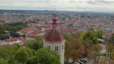 Aerial-view-close-up-orbit-around-historic-hilltop-Glokenturm-tower-on-Graz's-Schloßberg-with-views-across-the-city