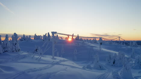 Präzise-Luftaufnahme,-Die-Bei-Sonnenaufgang-Zwischen-Schneebedeckten-Kabeln-In-Einer-Eindringlichen-Außerirdischen-Alpinen-Winterwaldlandschaft-Fliegt