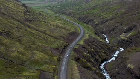 Car-driving-on-winding-road-in-the-mountains-of-Iceland-with-drone-video-following