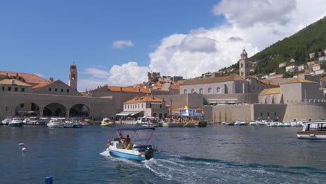 Handheld-Einspielaufnahme-Des-Alten-Hafens-Von-Dubrovnik-Mit-Einem-Vorbeifahrenden-Kleinen-Boot-Im-Vordergrund-An-Einem-Sonnigen-Sommertag-In-Kroatien