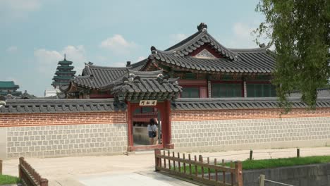 Gyeongbokgung-Palace---Korean-couple-traveler-enter-Hamhwadang---Korean-traditional-old-style-royal-hanok-building---panning-shot