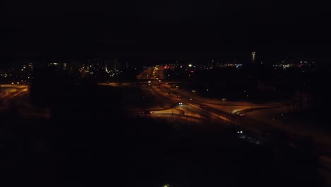 Night-aerial-flight-over-divided-highway-traffic-through-winter-city