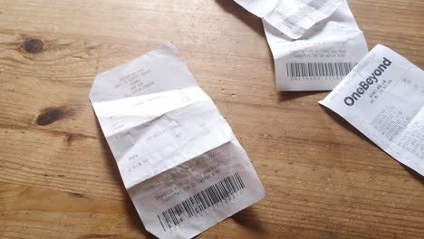 Falling-pile-of-receipts-on-wooden-table-UK-cost-of-living-crisis