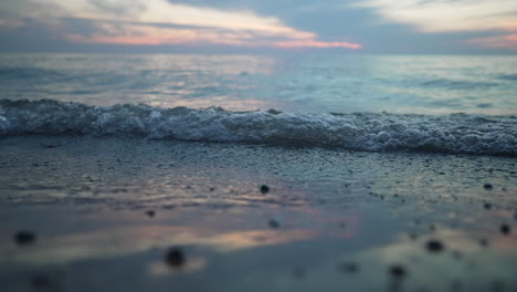 Small-waves-of-water-roll-into-the-shore-in-slow-motion-at-a-cloudy-golden-hour