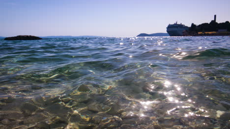 Crystal-Clear-sea-water-is-shimmering-in-the-sunlight-as-a-ferry-docks-at-the-harbour