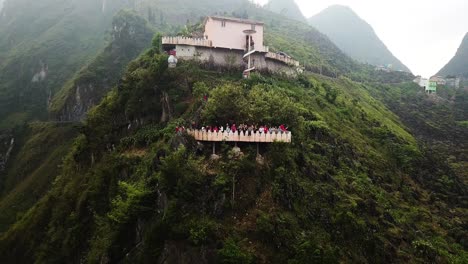 Reverse-reveal-aerial-shot-of-tourists-waving-from-a-spectacular-lookout-at-the-mountainous-Ma-Pi-Leng-Pass-Vietnam