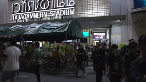 Spectators-leaving-Rajadamnern-Stadium-after-exiting-Muay-Thai-fights-in-Bangkok,-Thailand,-establishing-shot