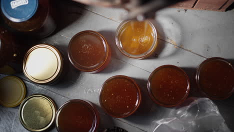 Top-Down-View-of-Pure-Honey-Glass-Jars,-Freshly-Extracted-Golden-Liquid-Bee-Honey-Flowing-and-Dripping-into-Bottles,-Traditional-Apiculture-Bio-Product,-Local-Production-in-Bee-Farm