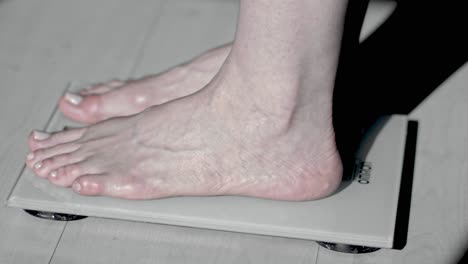 Close-up,-caucasian-person's-bare-feet-stepping-on-electronic-scale-at-home