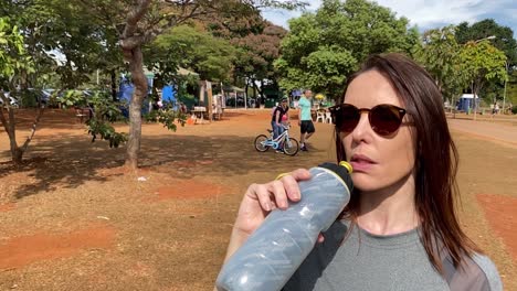 Zeitlupenaufnahme-Einer-Frau,-Die-Aus-Einem-Wasserbehälter-Im-Stadtpark-Von-Brasilia-In-Brasilien-Trinkt